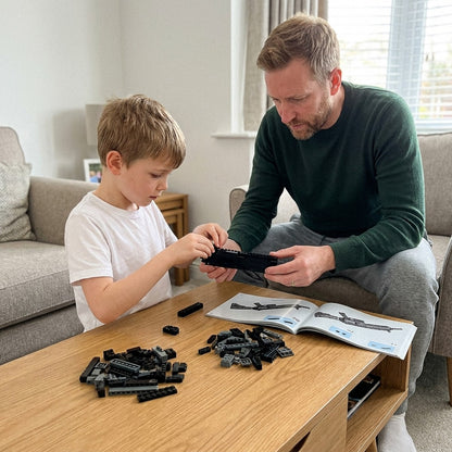Father and son building the HK-416-D brick kit together at the coffee table