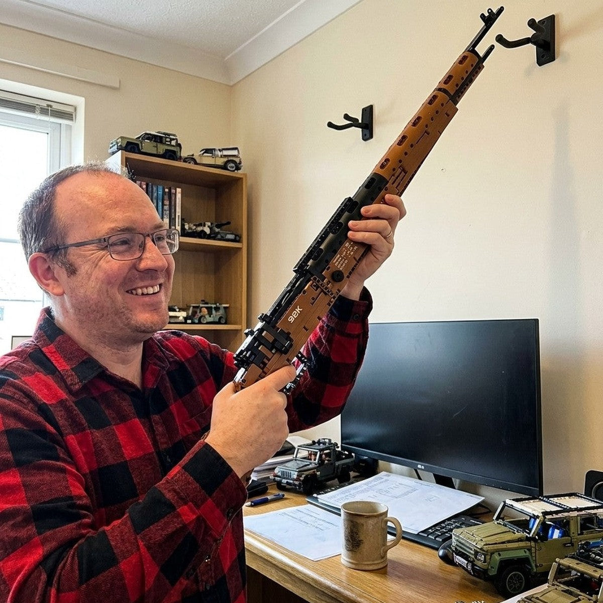 Karabiner 98K brick model being hung on wall display hooks in a home office