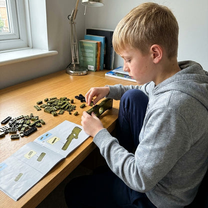 Boy building the Super Magnum brick kit himself at his desk